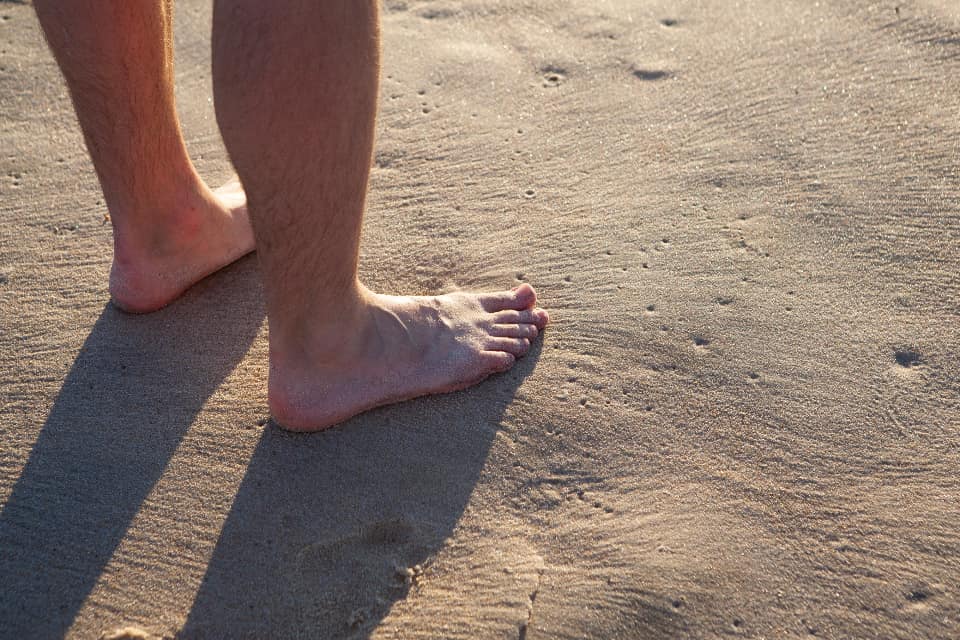 A very broad bare foot next to an extra-wide shoe last