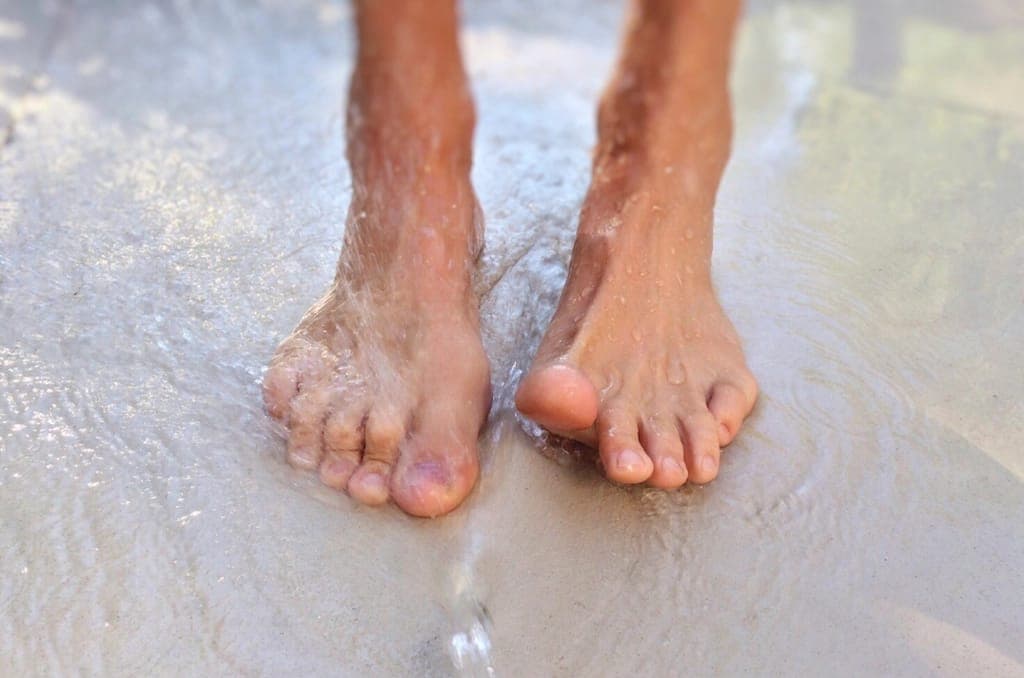 A slim bare foot beside a narrow-lasted minimalist shoe