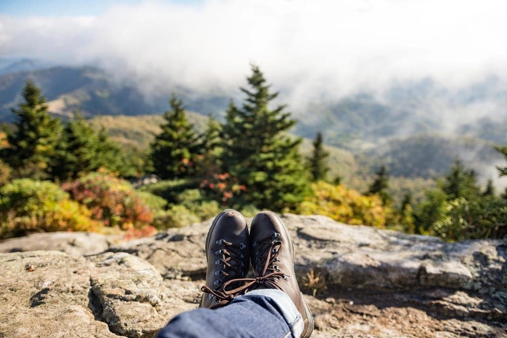 A stiff hiking boot beside a flexible minimalist trail shoe