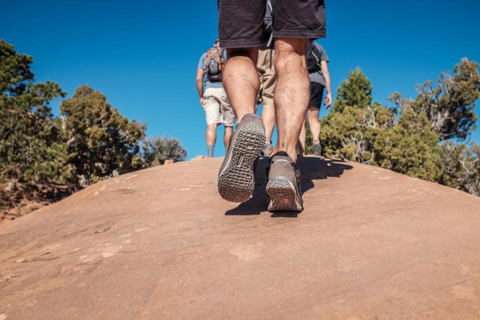 A soft, very wide hiking shoe on a grassy hillside