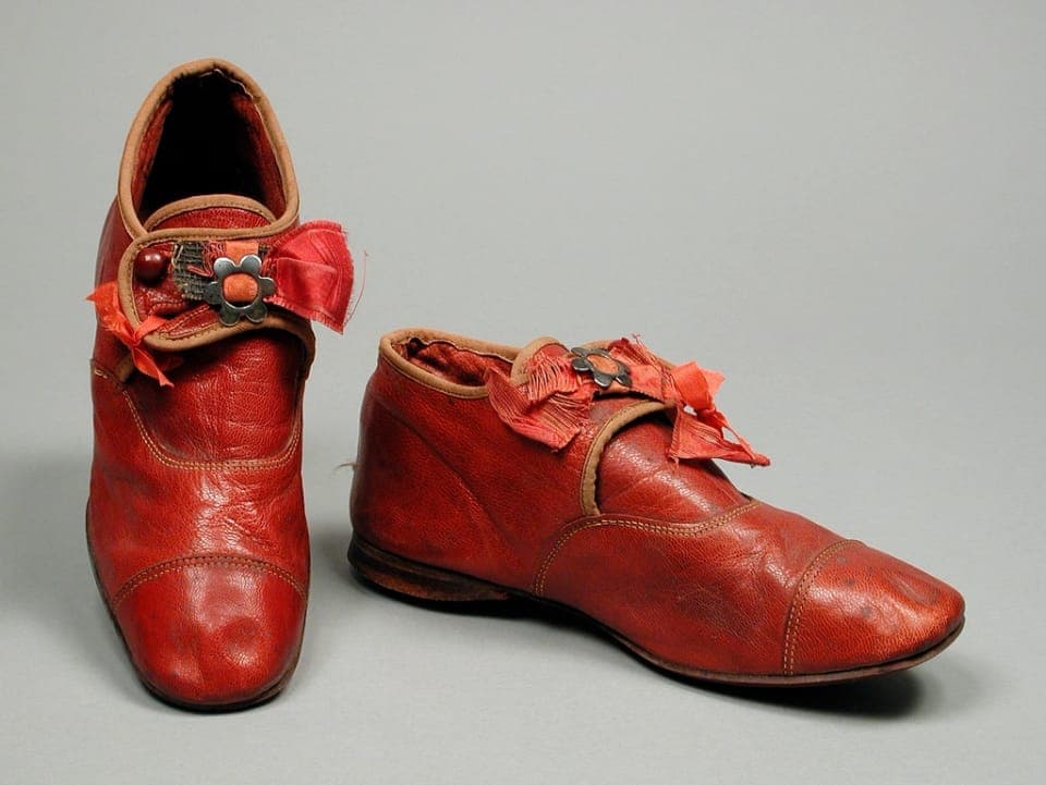 A toddler's wide, flexible barefoot shoe held in an adult hand
