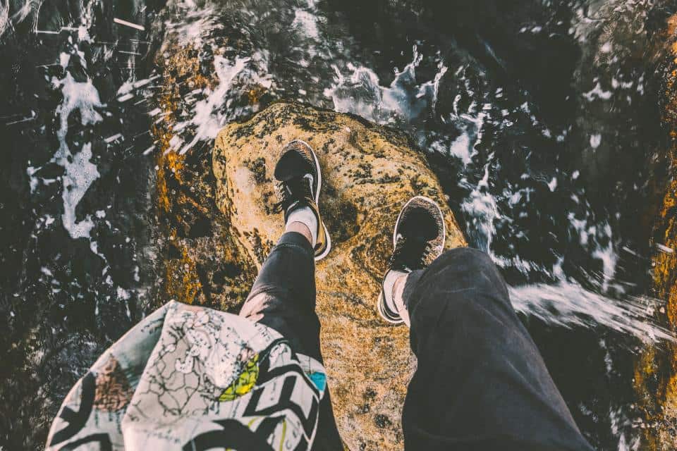 A knit water shoe at the edge of a shallow stream