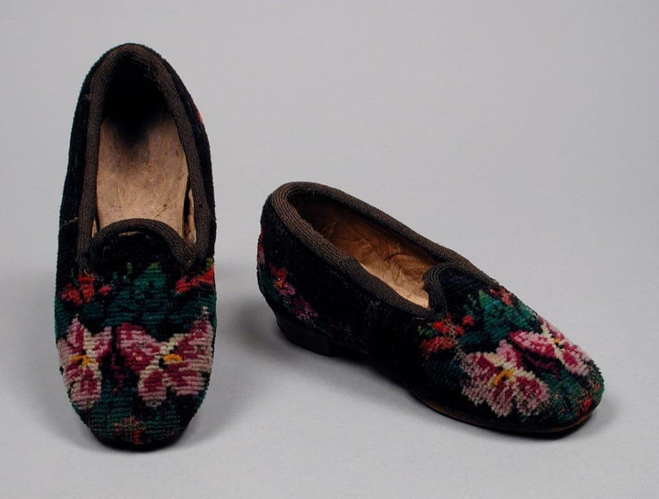 A child's stretch-knit wide barefoot shoe on a wooden step