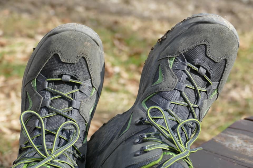 A trail-running shoe with a toe bumper standing on rocky ground